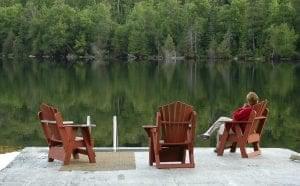 three wooden chairs with on occupied over looking a lake
