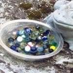 bowl full of water and marbles next to frog statue