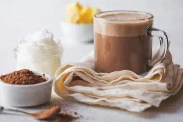 Cup of cocoa with cocoa powder on the side and whipped cream on the side